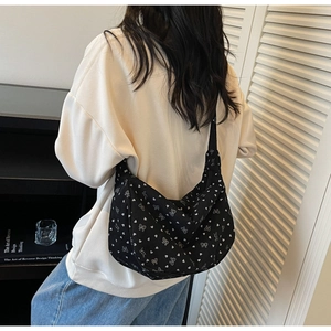 Black corduroy crossbody bag with white heart and bow prints shown on a model