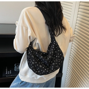 Detail of black corduroy hobo bag with white heart and bow floral patterns on model