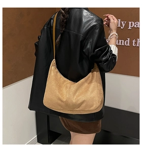 Detail of warm brown matte tote bag showing suede texture and vertical stitching on model