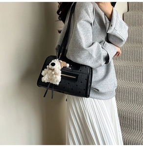 Detail of black polka dot tote bag with gold zipper and teddy bear charm on model