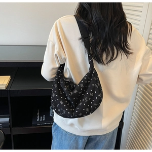 Detail of black corduroy crossbody bag with heart and bow patterns worn by a model