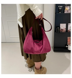 Detail of dark rose suede hobo bag featuring adjustable wide shoulder strap and metal buckle