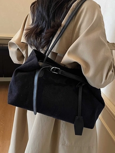 Minimalist black suede tote bag with slim straps worn with a trench coat for a stylish look