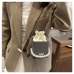 Detail of leopard print bucket bag with pearl handle, drawstring closure and chain strap