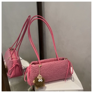 Detailed view of pink plush shoulder bag with bow accents and cute monster charm accessory
