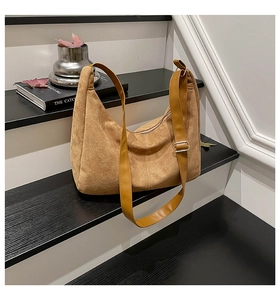 Close-up of brown suede hobo bag featuring silver hardware and a top zipper closure