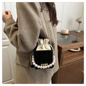 Detail of leopard print bucket bag with pearl handle and golden chain on a model