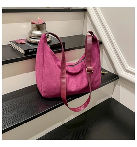 Detail of fuchsia suede hobo bag with adjustable leather strap on a wooden staircase
