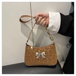 Close-up of leopard print baguette bag with suede texture and metallic butterfly detail