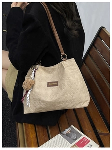 Détail du sac cabas en toile beige matelassé avec breloque ours et foulard sur banc