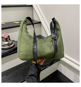 Detail of dark green suede hobo bag with adjustable black shoulder strap and gold buckle