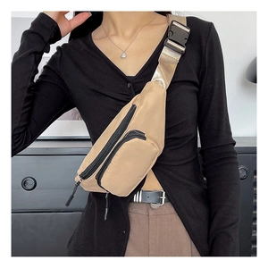 Detail of khaki nylon chest bag with black zippers and adjustable gold strap with buckle