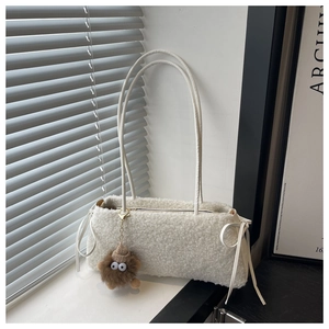 Detail of white faux fur shoulder bag with leather bows and brown monster plush charm