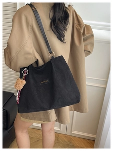 Détail du sac cabas matelassé noir avec écusson et accessoire ours en peluche