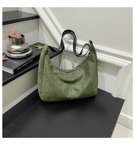 Detail of forest green frosted suede tote bag with adjustable black strap on steps
