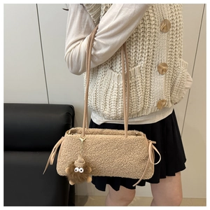 Detail of beige fleece shoulder bag with long straps and a brown plush doll pendant