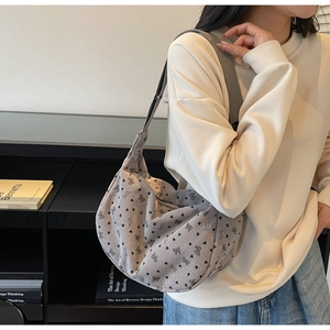 Detail of grey corduroy hobo bag with printed bow and heart patterns on shoulder strap