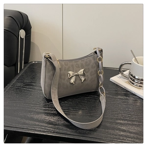 Detail of grey leopard embossed crossbody bag with metallic silver bow and decorative chain