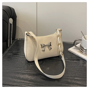 Detail of off-white underarm bag with silver bow buckle and white chain strap