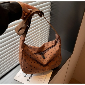 Detail of brown corduroy hobo bag with black heart and bow prints on wide shoulder strap