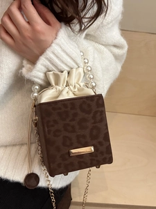 Leopard print bucket bag with pearl handle and gold chain strap on white sweater