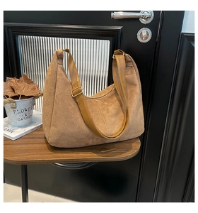 Detail of tan suede hobo bag with adjustable leather strap and gold buckle on a table