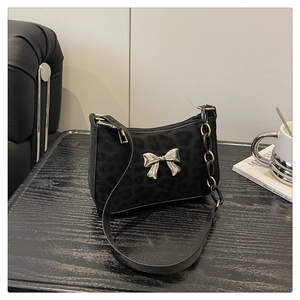 Detail of black leopard pattern shoulder bag with silver metal bow and chain strap