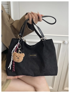 Gros plan du sac cabas matelassé noir avec étiquette Creative Cat et breloque ours