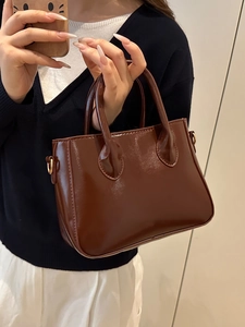 Polished dark brown handheld bag with glossy finish and chic metallic gold hardware