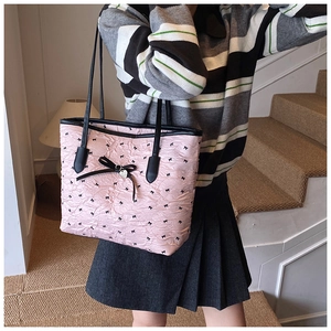 Détail du sac cabas rose avec imprimé nœuds noirs et pendentif cœur en métal