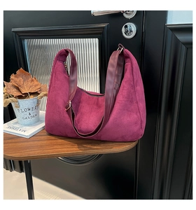 Close-up of matte dark red suede tote bag on wooden table with elegant home decor
