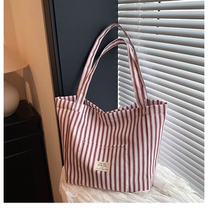 Detail of red and white striped canvas tote bag showing front pocket and woven label