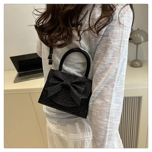 Dettaglio mini borsa da sera nera glitterata con fiocco 3D e design a doppio manico