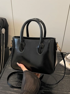 Glossy black patent leather tote bag with gold hardware and a detachable shoulder strap