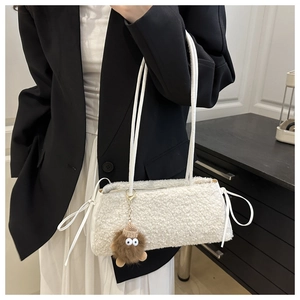 Close-up of a white plush shoulder bag with bow details and a cute brown monster charm