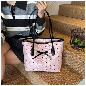 Sac fourre-tout rose avec motifs de nœuds présenté de profil porté par un modèle