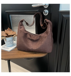 Detailed view of brown matte suede hobo bag texture and stitching on dark wood table