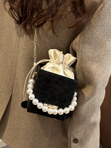 Leopard print bucket bag with pearl handle and gold chain strap on brown wool coat