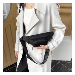Close-up of black oxford fabric waist bag with dual zippers worn over a white coat