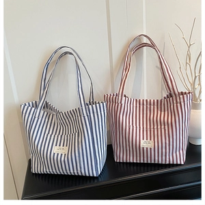 Close-up of blue and red striped canvas tote bags with front pockets and decorative labels