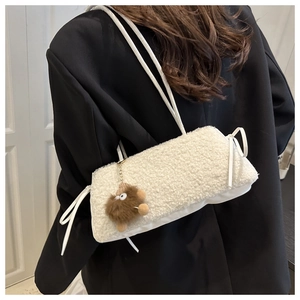 Detail of white faux fur shoulder bag with a brown plush monster charm on black blazer