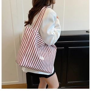Detail of red and white striped canvas tote bag showing the front pocket and fabric texture