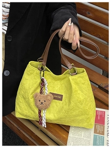 Détail du sac cabas matelassé vert citron avec anses en cuir marron et breloque ours peluche