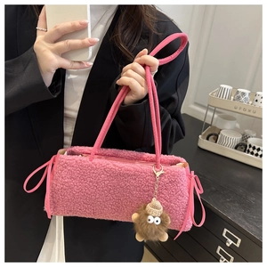 Close-up of pink plush shoulder bag featuring a ribbon bow and a cute monster charm