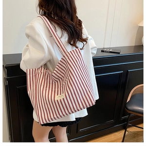 Detail of red and white striped canvas tote bag showing textured fabric and logo patch