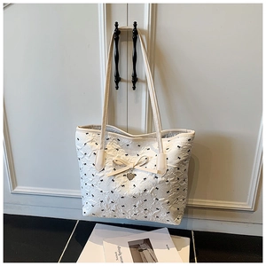Détail du sac cabas matelassé blanc avec imprimés nœuds et pendentif en cœur doré