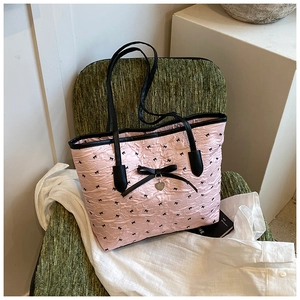 Détail du sac cabas plissé rose avec nœuds noirs et pendentif en forme de cœur argenté