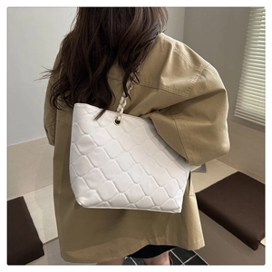 Detail of white quilted oversized shoulder bag with gold chain strap on a model
