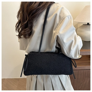 Detail of black fuzzy plush shoulder bag with decorative side ribbons and bows