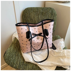 Vue détaillée du sac cabas rose avec motifs de nœuds noirs et breloque en métal en cœur